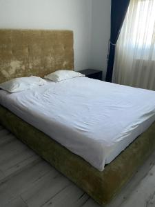 een bed met witte lakens en kussens in een slaapkamer bij Apartament AVANA in Oradea