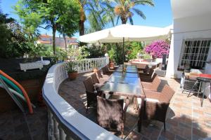 eine Terrasse mit Tischen, Stühlen und einem Sonnenschirm in der Unterkunft Villa Sitges Palm Garden: 5 minutes walking from beach. Amaizing Garden/Outdoor in Sitges