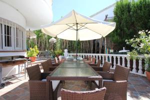 einen Tisch und Stühle mit Sonnenschirm auf einer Terrasse in der Unterkunft Villa Sitges Palm Garden: 5 minutes walking from beach. Amaizing Garden/Outdoor in Sitges