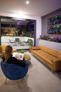 una donna seduta su una sedia blu in un soggiorno di Moody smart & comfy Hotel a Terranuova Bracciolini