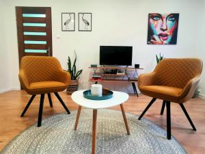 two chairs and a coffee table in a living room at Artic Home Apartman-nearby city center! in Pécs