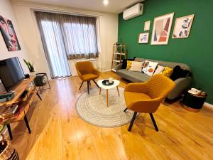 ein Wohnzimmer mit einem Sofa, Stühlen und einem TV in der Unterkunft Artic Home Apartman-nearby city center! in Pécs