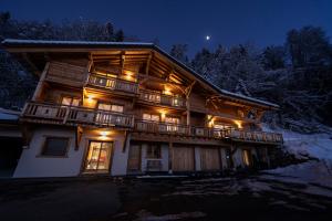a large wooden house with a balcony at night at Chalet Arpitan - les Carroz - Grand Massif in Les Carroz d'Araches