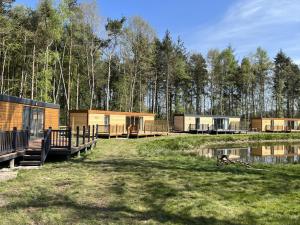 a group of lodges in the woods next to a pond at Rowan Boutique Lodge for couples with a dog in York
