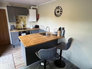 a kitchen with a sink and a counter with two chairs at Rowan Boutique Lodge for couples with a dog in York