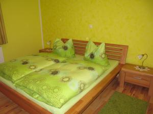 a bed with a green comforter and pillows on it at Ferienwohnungen Haus Bliem in Lieserhofen