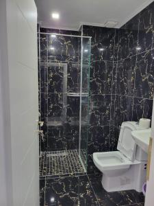 Baño de azulejos negros con aseo y lavamanos en Vila Chelsea, en Ksamil