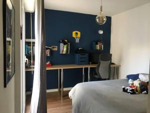 ein Schlafzimmer mit einer blauen Wand, einem Bett und einem Schreibtisch in der Unterkunft Cap Corse : Très bel appartement en bord de mer in Santa-Maria-di-Lota