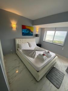 a bedroom with a large white bed with a window at SEA FRONT in Armação de Pêra