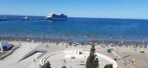 un groupe de personnes sur une plage avec un bateau de croisière dans l'établissement Enjoy Departamento Frente al Mar, à Puerto Madryn