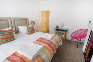 a bedroom with two beds and a pink chair at Paskins, Cowes - Sleeps 4 - 2 Bed - 2 Bath - Central Location in Cowes