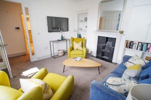 a living room with a blue couch and yellow chairs at Paskins, Cowes - Sleeps 4 - 2 Bed - 2 Bath - Central Location in Cowes
