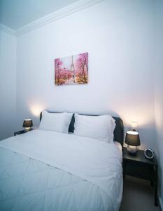Un dormitorio con una cama blanca y una pintura en la pared en Angie's House Volos, en Volos