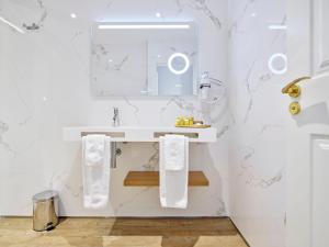Baño blanco con lavabo y espejo en Hotel Boutique Adolfo, en Toledo