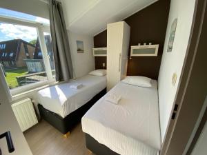 a small room with two beds and a window at Zeester - Wijk de Brabander 91 in Cadzand