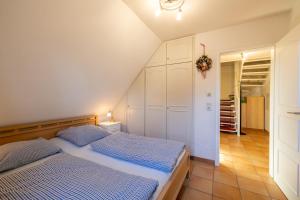 Cette chambre comprend un lit avec des draps bleus et un placard. dans l'établissement Ferienwohnung Brise, à Wyk auf Föhr
