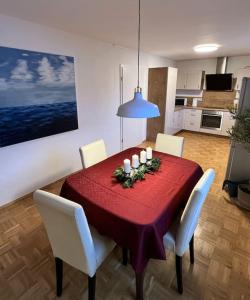 a dining room table with a red tablecloth and white chairs at Garten-Ferienwohnung Seppi in Tutzing