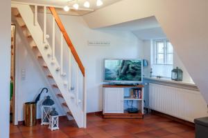 ein Wohnzimmer mit einem TV und einer Treppe in der Unterkunft Ferienwohnung Britta in Wyk auf Föhr