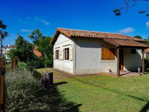 una pequeña casa blanca con un patio de césped en Casa a 3 cuadras del mar, zona centro en Villa Gesell