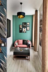 a living room with a pink couch and a green wall at Les Appartements de la Nef d'Or in Saint-Quentin