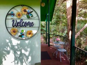 a patio with a sign that says welcome and a table at Linger a While Chalet on Gallery Walk with Spa, Fireplace, WiFi & Netflix in Mount Tamborine
