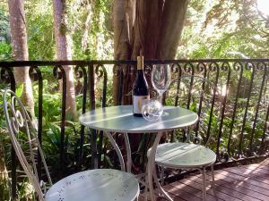 una mesa con una botella de vino y dos copas en Linger a While Chalet on Gallery Walk with Spa, Fireplace, WiFi & Netflix, en Mount Tamborine
