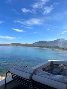 a couch sitting on a deck overlooking a body of water at Hôtel Serenada in Algajola