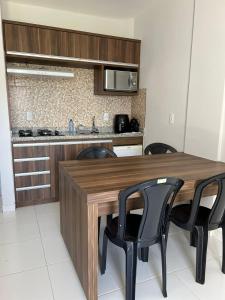 a kitchen with a wooden table and black chairs at Lagoa Quente Flat Service in Caldas Novas