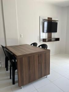 a wooden table with chairs and a television on a wall at Lagoa Quente Flat Service in Caldas Novas