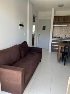 a living room with a brown couch and a kitchen at Lagoa Quente Flat Service in Caldas Novas