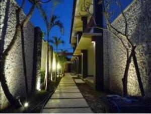 Une allée avec des bâtiments et des palmiers la nuit dans l'établissement 21 Lodge, à Nusa Dua