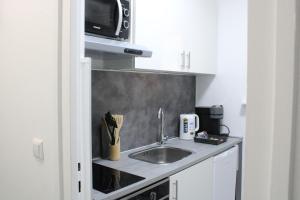eine Küche mit einer Spüle und einer Mikrowelle in der Unterkunft Schickes Appartement an der Neckarpromenade in Heilbronn
