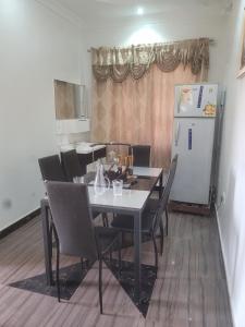 a dining room table with chairs and a refrigerator at BENJI'S VILLA in Kumasi