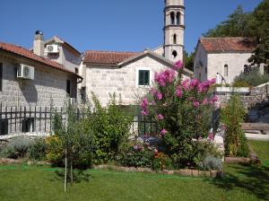 un jardin en face d'une église avec une tour dans l'établissement Guest House Dragutinovic, à Perast