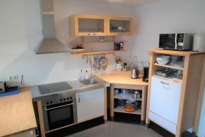 eine kleine Küche mit weißen Geräten und Holzschränken in der Unterkunft Orka - Wijk de Brabander 93 in Cadzand