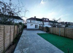 a backyard with a white house and a fence at Homely & Peaceful Living Space in Morden