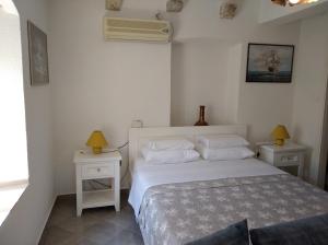 um quarto com uma cama branca e duas mesas de cabeceira em Guest House Dragutinovic em Perast