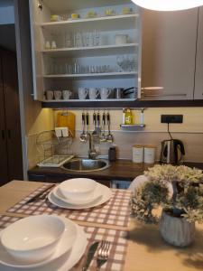 uma cozinha com uma mesa com pratos e um lavatório em Tim 135 Konaci-Angella Centar em Kopaonik