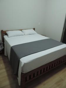 1 cama grande con sábanas blancas y almohadas. en Pousada Vale do Parque, en Cunha