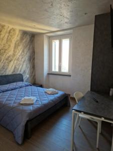 um quarto com uma cama, uma mesa e uma janela em Piazza Duomo em Tuscania