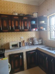 a kitchen with wooden cabinets and a microwave on the counter at BENJI'S VILLA in Kumasi