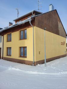 um edifício amarelo com uma luz de rua na neve em Apartmány 009 em Borová Lada