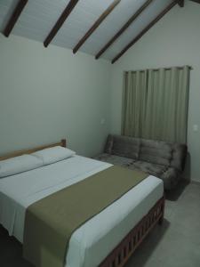 sypialnia z dużym łóżkiem i kanapą w obiekcie Pousada Vale do Parque w mieście Cunha