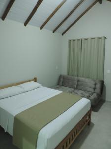 een slaapkamer met een groot bed en een bank bij Pousada Vale do Parque in Cunha
