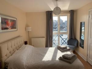 a bedroom with a bed and a chair and a window at Fabulously located Marina apartment - marina views in Pevensey