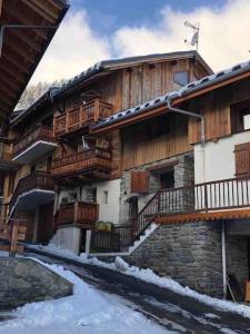 een groot houten gebouw met sneeuw ervoor bij Meribel Chalet de Séverine in Les Allues