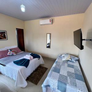 a bedroom with two beds and a tv on the wall at Pousada La Belle de Jour in Chapada dos Guimarães