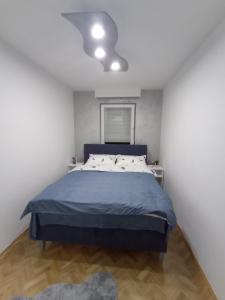 a bedroom with a blue bed and a white wall at STAN NA DAN BIJELJINA in Bijeljina