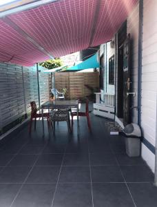 eine Terrasse mit einem Tisch, Stühlen und einem Sonnenschirm in der Unterkunft Montabo duplex in Cayenne