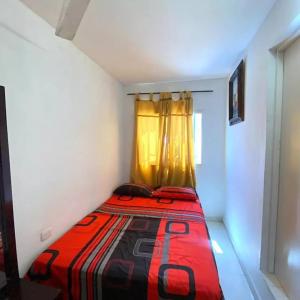 um pequeno quarto com uma cama vermelha e uma janela em 2023 Apartamento Amoblado 4 Habitaciones Familias- Grupos 8 a 9 Personas em Santa Marta